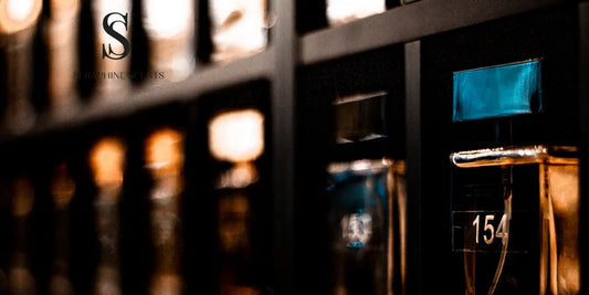 Glass perfume bottles on black shelves, reflecting a warm glow — Seraphine Scents Singapore