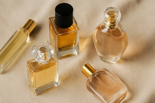 Four elegant perfume bottles arranged on soft beige fabric, showcasing a variety of feminine fragrance designs and bottle shapes.
