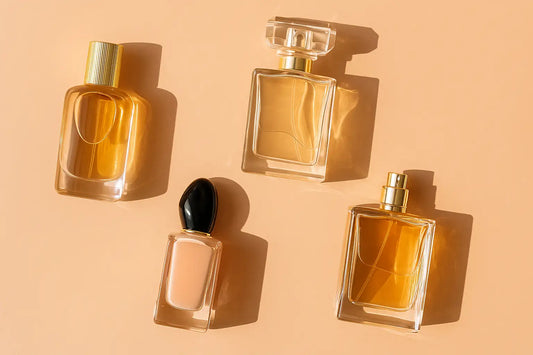 A digital photograph displays four uniquely designed perfume bottles arranged on a soft peach background, representing affordable luxury fragrance options in Singapore.